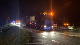 Castor-Transport auf Zufahrtstraße, im Hintergrund Einsatzfahrzeuge der Polizei