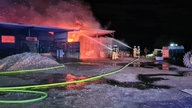 Das brennende Gebäude auf der Schaf-Farm, mehrere Feuerwehrleute sind bei den Löscharbeiten