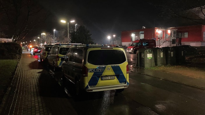 Das Bild zeigt mehrere Polizeiwagen in einer dunklen Straße