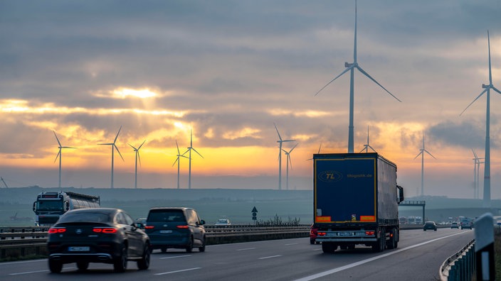 Autos und LKW auf der A44 mit Tagebau und Windrädern im Hintergrund