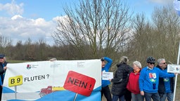 Anwohner protestieren mit großem Schild gegen das Hochwasserschutzprojekt