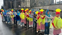 Eine lange Schlange kostümierter Menschen steht vor dem Dom