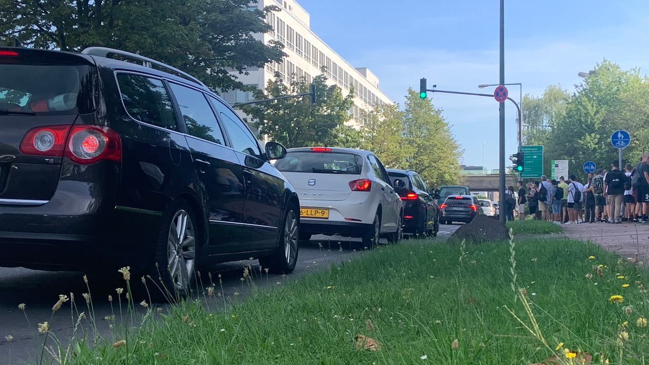 Autos stehen im Stau. Eine Menschentraube steht auf dem Gehweg.