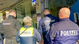 Eine Gruppe aus Polizisten und Ordnungsamt steht vor einem Geschäft