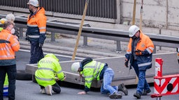 Polizeibeamte der Kriminalpolizei prüfen eine Betonplatte auf der A3