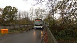 Gelenkbus fährt über schmale, alte Brücke