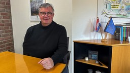 Niederkrüchtens Bürgermeister, Karl-Heinz Wassong, sitzt im Rathaus an einem Tisch.