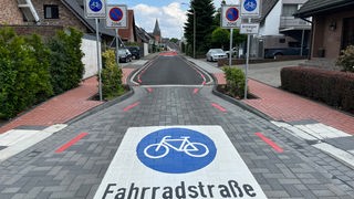 Eine rot markierte Fahrradstraße mit Straßenschildern auf beiden Seiten 