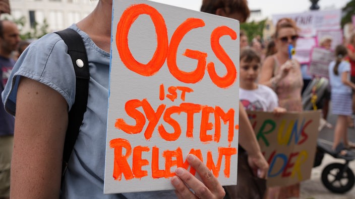 In orangener Schrift auf weißem Grund steht: OGS ist systemrelevant.