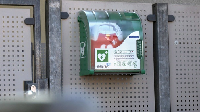 Ein erste-Hilfe-Kasten mit Defibrillator an einer Wand.