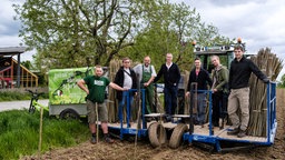 Mehrere Menschen stehen auf einem landwirtschaftlichen Arbeitsgerät.