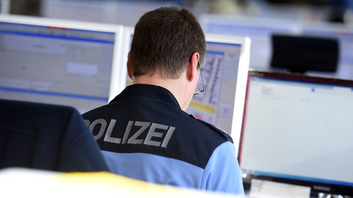 Ein Polizist sitzt vor einem Monitor.