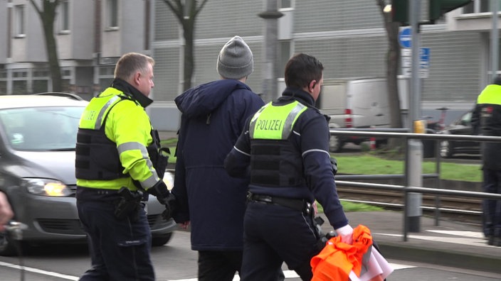 Zwei Polizisten führen einen Aktivisten der letzten Generation ab 