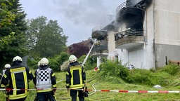 Einsatzkräfte vor einem brandgeschädigten Mehrfamilienhaus