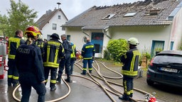 Einsatzkräfte vor einem brandgeschädigten Mehrfamilienhaus