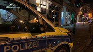 Polizisten vor und in einem Kisok bei Nacht.