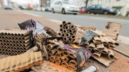 Reste von Silvesterböllern liegen auf einer Straße mit Autos