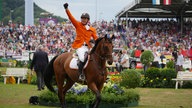 Der Sieger im Springreiten reitet mit erhobener Faust durch das Stadion.