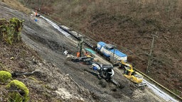 mehrere Bagger und andere Großgeräte stehen an und auf einer Gleisstrecke