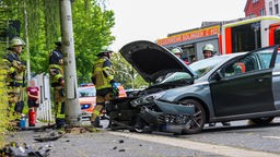 Das Foto zeigt die Unfallstelle mit verunfalltem Auto und Feuerwehrleuten.