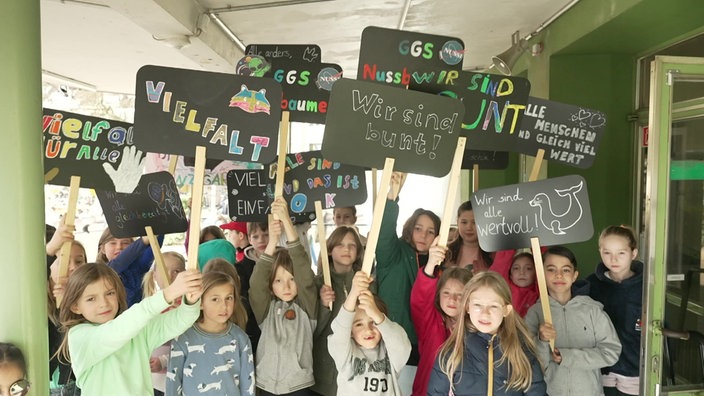 Schulkinder strecken Plakate gegen Rassismus in die Höhe 