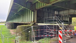 Eine lange Brücke von unten, dazu viele Baustellenabsperrungen