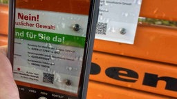 Ein Smartphone macht eine Kameraaufnahme von einer Infoplakette.