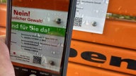 Ein Smartphone macht eine Kameraaufnahme von einer Infoplakette.