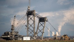 Im Vordergrund ein Braunkohlebagger im Tagebau Hambach, im Hintergrund ein Kraftwerk