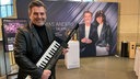 Thomas Anders mit einem Umhängepiano in der Hand vor einem großen Banner und einer Vitrine mit Ausstellungsstücken