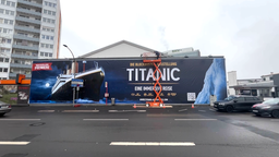 Ein Plakat der Titanic-Ausstellung wird in Köln aufgehangen