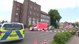 Das Foto zeigt mehrere Polizeifahrzeuge und Rettungswagen auf einer Straße, die mit Absperrband abgesperrt wurde