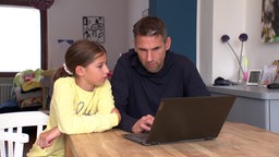 Vater und Tochter stzen vor einem Laptop