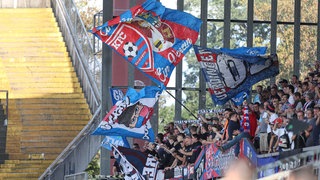 Fans des KFC Uerdingen in der Krefelder Grotenburg. Sie schwenken große Fahnen auf einer Tribüne.