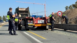 Polizisten stehen auf einer Autobahn neben einem Lastkraftwagen