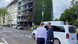 Oberbürgermeister Keller auf der Straße im Gespräch, im Hintergrund das brandgeschädigte Haus.