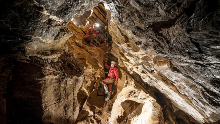 Ein Kletterer klettert in der Windlochhöhle 