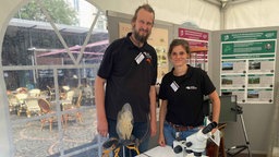 Ein Mann und eine Frau stehen vor mehreren bunten Plakaten