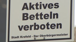 Auf dem Foto ist ein Schild mit der Aufschrift "Aktives Betteln verboten" der Stadt Krefeld.