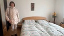 Frau lächelt in Kamera während sie in ihrem Schlafzimmer steht 