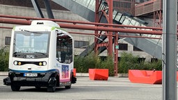 kleiner weißer Bus, der autonom fährt, parkt auf dem Gelände der Zeche Zollverein