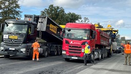 Mehrere LKW und Arbeiter auf der Autobahn