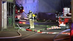 Feuerwehrleute stehen mit Atemschutz vor dem brennenden Gebäude