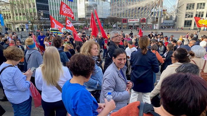 Eine Menschenmenge ist zu sehen. Im Hintergrund viele rote Fahnen von unter anderem SPD und Jusos.