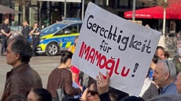 Die Teilnehmenden an der Demonstration halten Plakate hoch. Es ist zu lesen: "Gerechtigkeit für Imamoglu!"