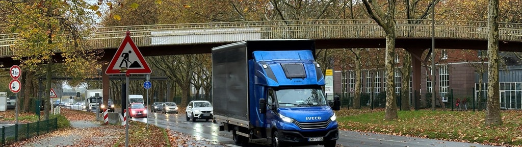 Fußgängerbrücke über die B1 mit einem Baustellenbild im Vordergrund und mehreren Farhrzeugen auf einer Fahrbahn der B1