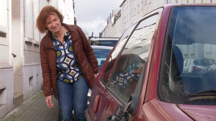 Die Dortmunderin Elke Meinert an einem Schrottauto 