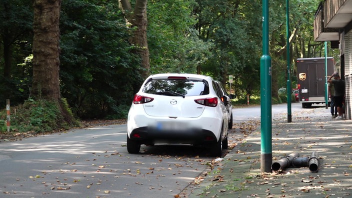 Pkws und ein Zustellfahrzeug stehen in der Straße, in der ein Zusteller in Duisburg angeriffen wurde.