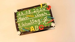 Eine Einschulungstorte sieht aus wie eine Tafel mit Aufschrift "22.08.2024 Mein 1.Schultag"