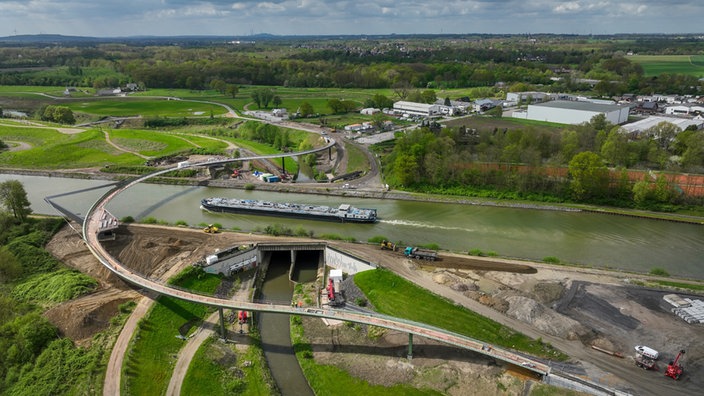 Eine Brücke führt über einen Fluss, ein Schiff ist auf dem Wasser unterwegs